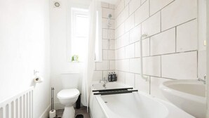 A modern bathroom with a toilet, bathtub, and sink. - House-sleeps8-parking-garden (Leeds)