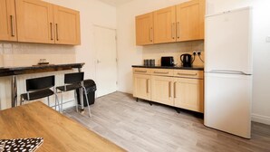 A compact kitchen with wooden cabinets, a white refrigerator, and a black countertop. - House-sleeps8-parking-garden (Leeds)