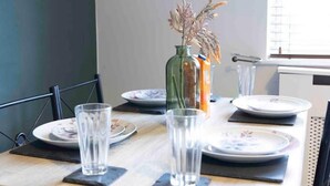 A dining table set with plates, glasses, and a vase with dried flowers. - House-sleeps7-parking-garden-petfriendly (Leeds)