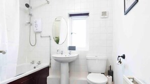A modern bathroom with a white sink, toilet, and bathtub. - House-sleeps7-parking-garden-petfriendly (Leeds)