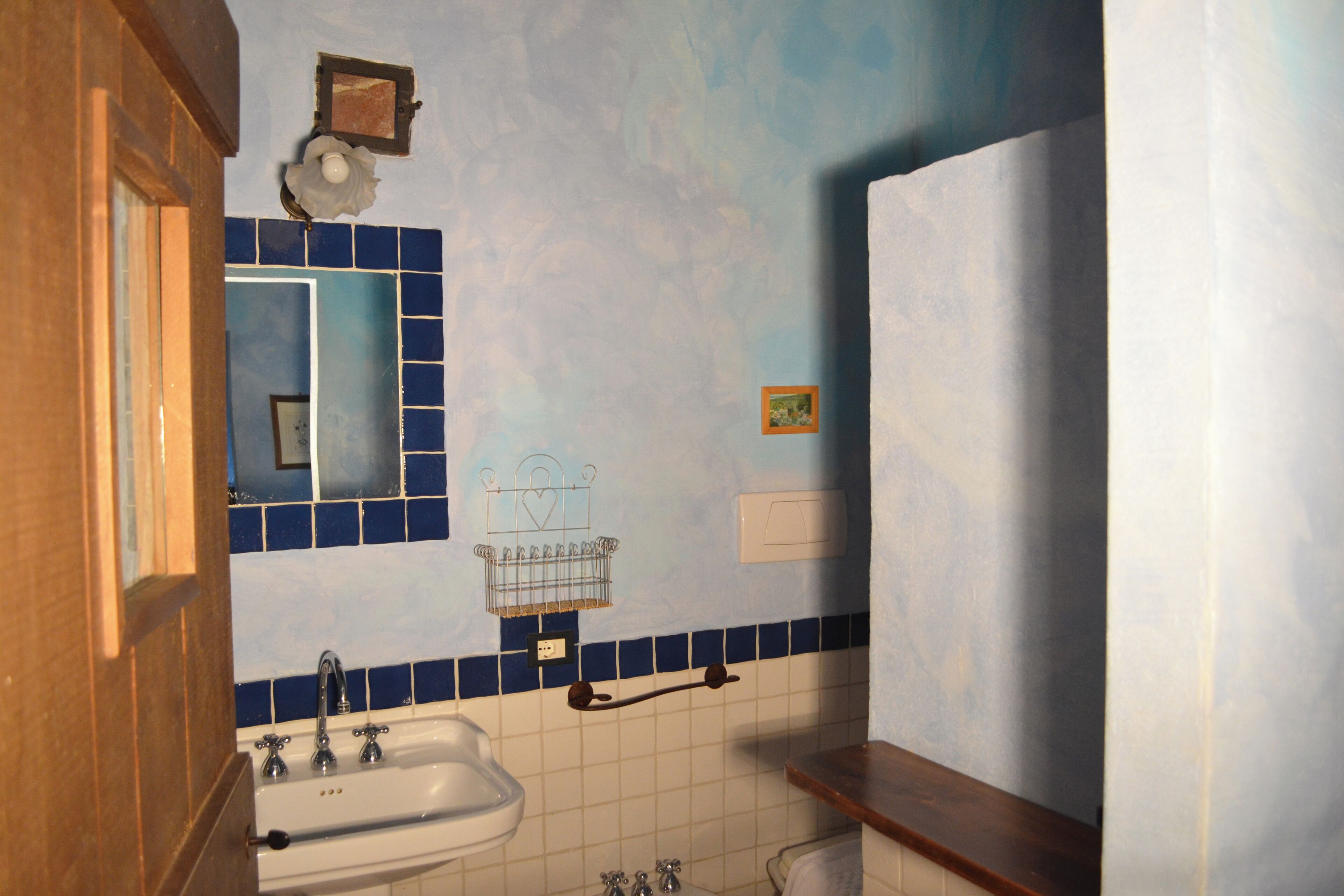 Un bagno con lavandino, specchio e parete rivestita in piastrelle blu.