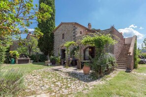 A stone building with a garden, a stone staircase, and a paved area. - Appartamento La Torretta Di Pietra (Monteleone d'Orvieto)