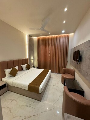 Une chambre d’hôtel moderne équipée d’un grand lit, d’un bureau, d’une chaise et d’un ventilateur de plafond.