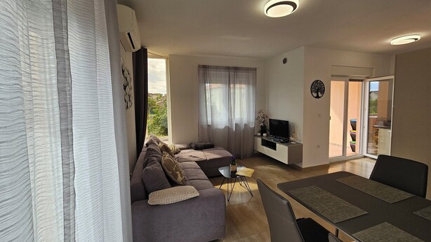 A modern living room with a sofa, TV, and dining area.