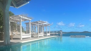 A clear blue pool with a wooden deck and a gazebo structure.