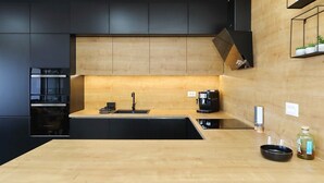Une cuisine moderne avec un plan de travail en bois, des meubles de rangement noirs et un four encastré.