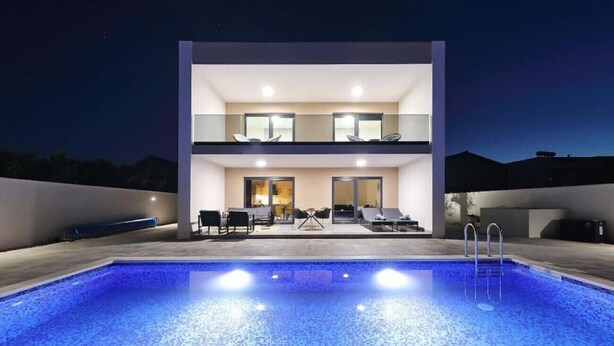 Un bâtiment moderne à deux étages, avec une piscine en premier plan.