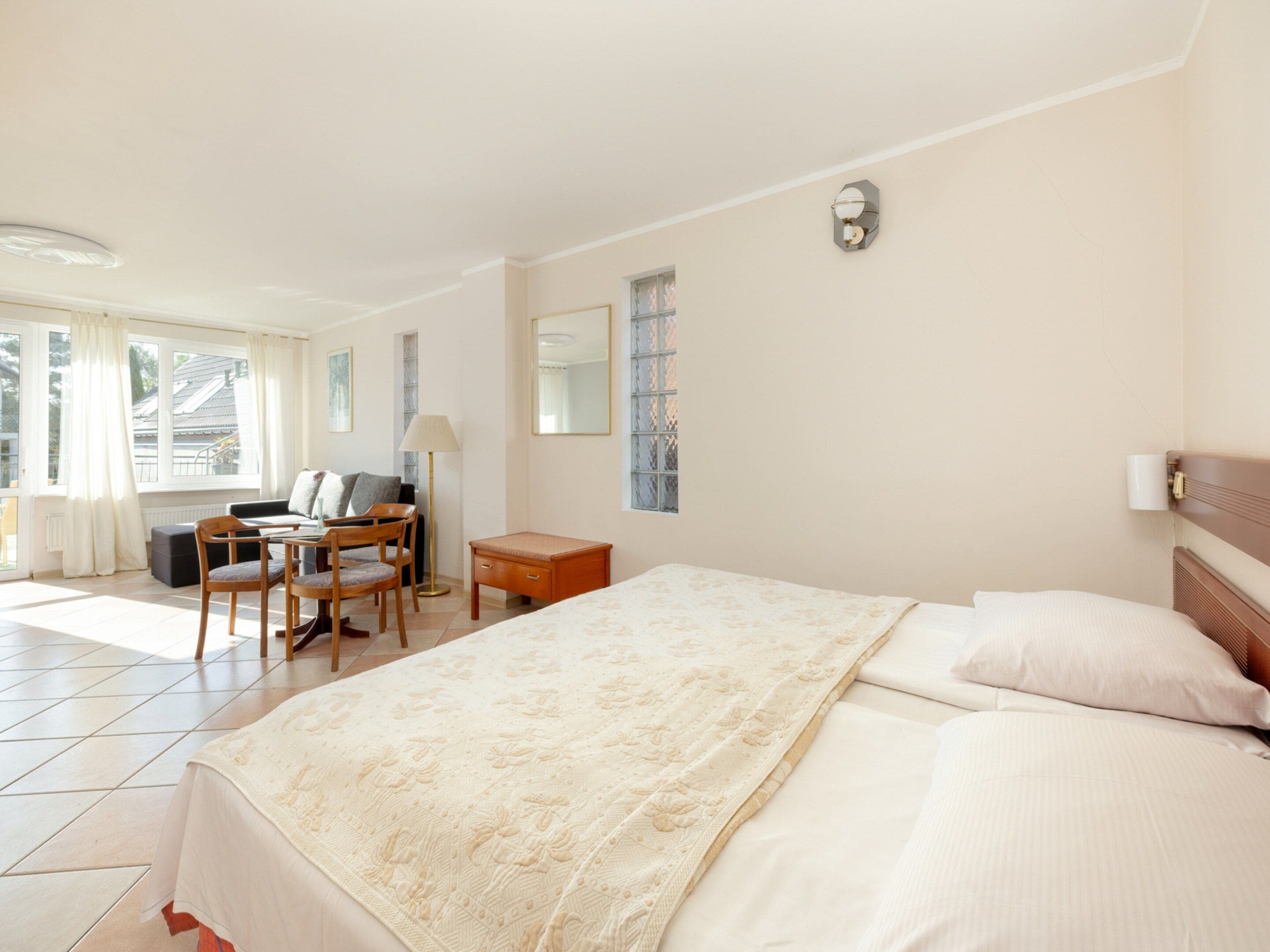 A hotel room with a large bed, a desk with a chair, a lamp, and a window with curtains.