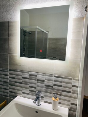 A bathroom with a rectangular mirror, a sink with a chrome faucet, and a toilet. - Modernly furnished vacation home in Posada (Posada)