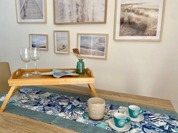 A wooden tray with two wine glasses, a decorative plate, and a vase on a table with a blue floral table runner. - Modernly furnished vacation home in Posada (Posada)