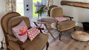 Una habitación acogedora con dos sillas de madera, una mesita y vistas al exterior a través de un ventanal.