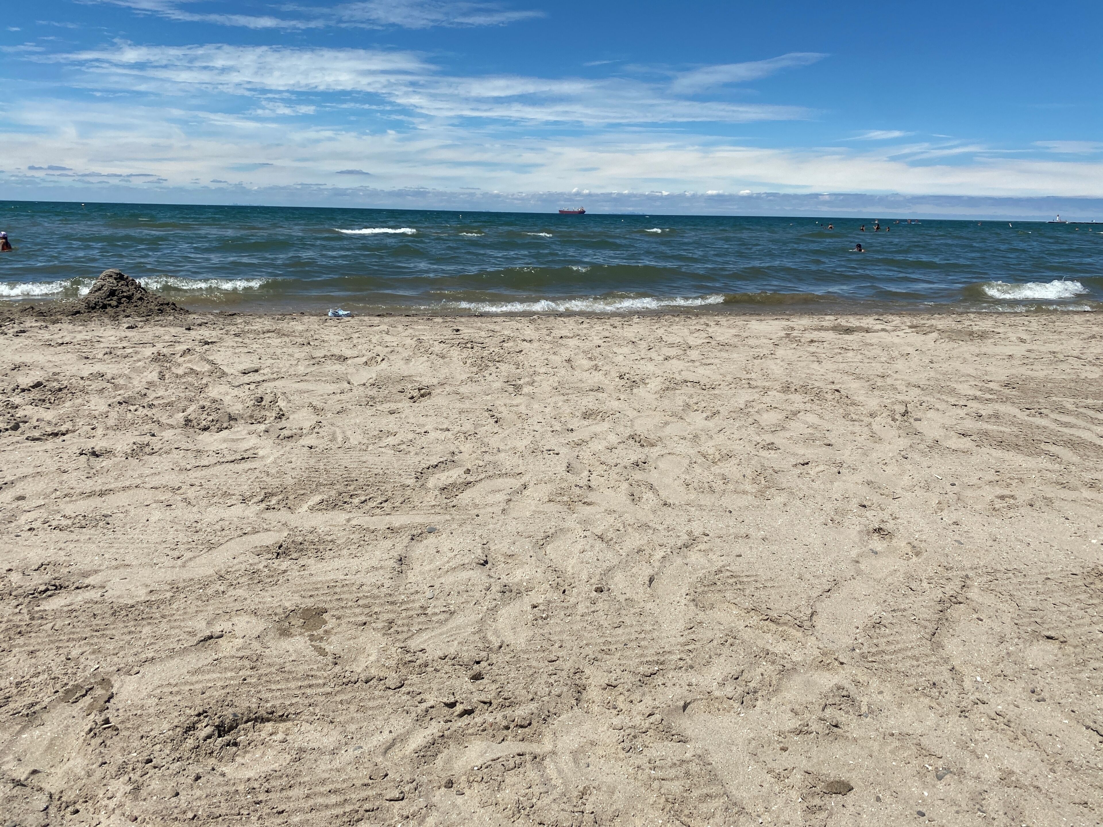 Une plage de sable où l’on peut voir des empreintes et d’où l’on a une vue dégagée sur l’océan.