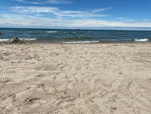 A sandy beach with visible footprints and a clear view of the ocean.