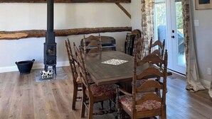 Un comedor rústico con una mesa y sillas de madera, una estufa negra y un ventilador de techo.