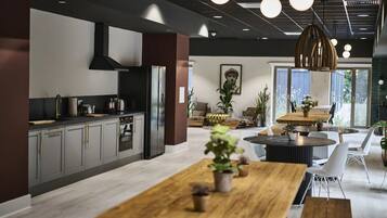 A modern kitchen with grey cabinets, a black refrigerator, and a wooden dining table with chairs.