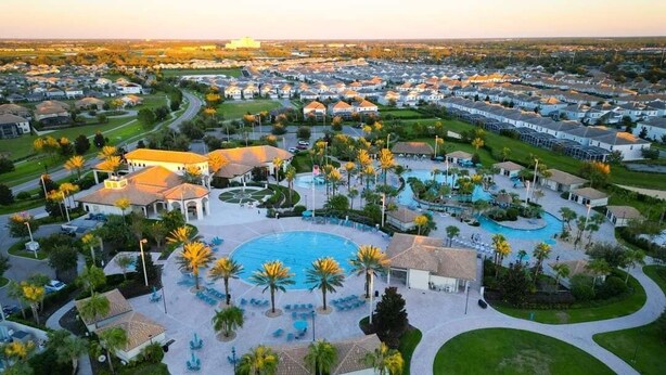 Vista aérea de una zona residencial con una piscina central rodeada de casas y vegetación.