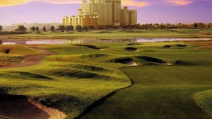 Un campo de golf con búnkeres y un edificio grande al fondo.