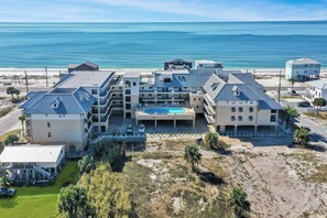 Un hotel frente a la playa con varias construcciones, piscina y vistas al océano.