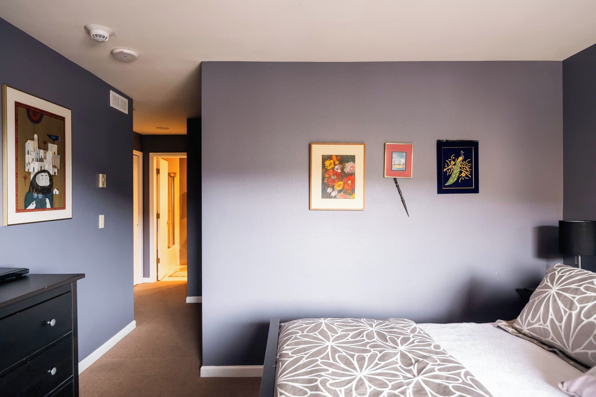 Une chambre à coucher avec un lit, une commode et un couloir menant à une autre pièce.