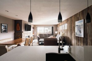 A modern kitchen with a central island, wooden accents, and pendant lighting.