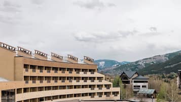 Un hôtel à plusieurs étages, doté d’un toit plat et de balcons, qui se dresse sur un fond de paysage montagneux.