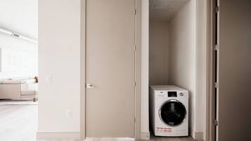 A laundry room with a washing machine, a door, and a light-colored floor.