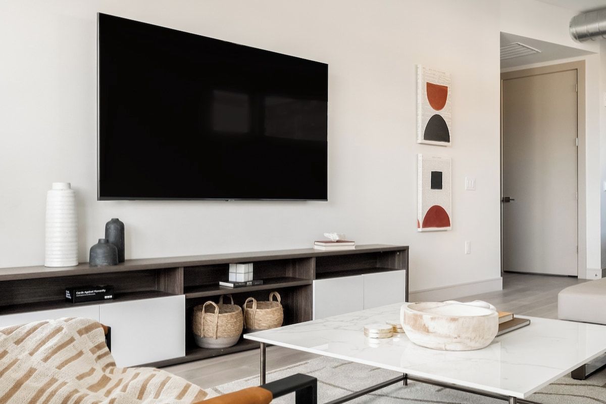 Una sala moderna con un televisor de pantalla plana montado en la pared, un sofá, una mesa de centro y una decoración de estilo minimalista.