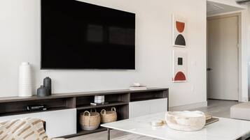 Una sala moderna con un televisor de pantalla plana montado en la pared, un sofá, una mesa de centro y una decoración de estilo minimalista.