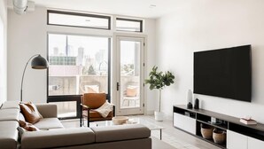 Uma sala de estar moderna com um sofá, poltrona e uma televisão grande na parede.