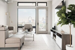A modern living room with a sofa, armchair, coffee table, and a large plant. - Penthouse Views | Walk to Empower Field | Tesoro (Denver)
