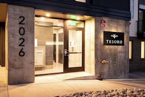 A hotel entrance with a glass door, a number '2026' sign, and a 'TESORO' sign on the wall. - Penthouse Views | Walk to Empower Field | Tesoro (Denver)