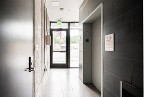 A hallway with a door leading to an outdoor area, a fire exit sign, and a sign indicating elevators are out of service. - Penthouse Views | Walk to Empower Field | Tesoro (Denver)
