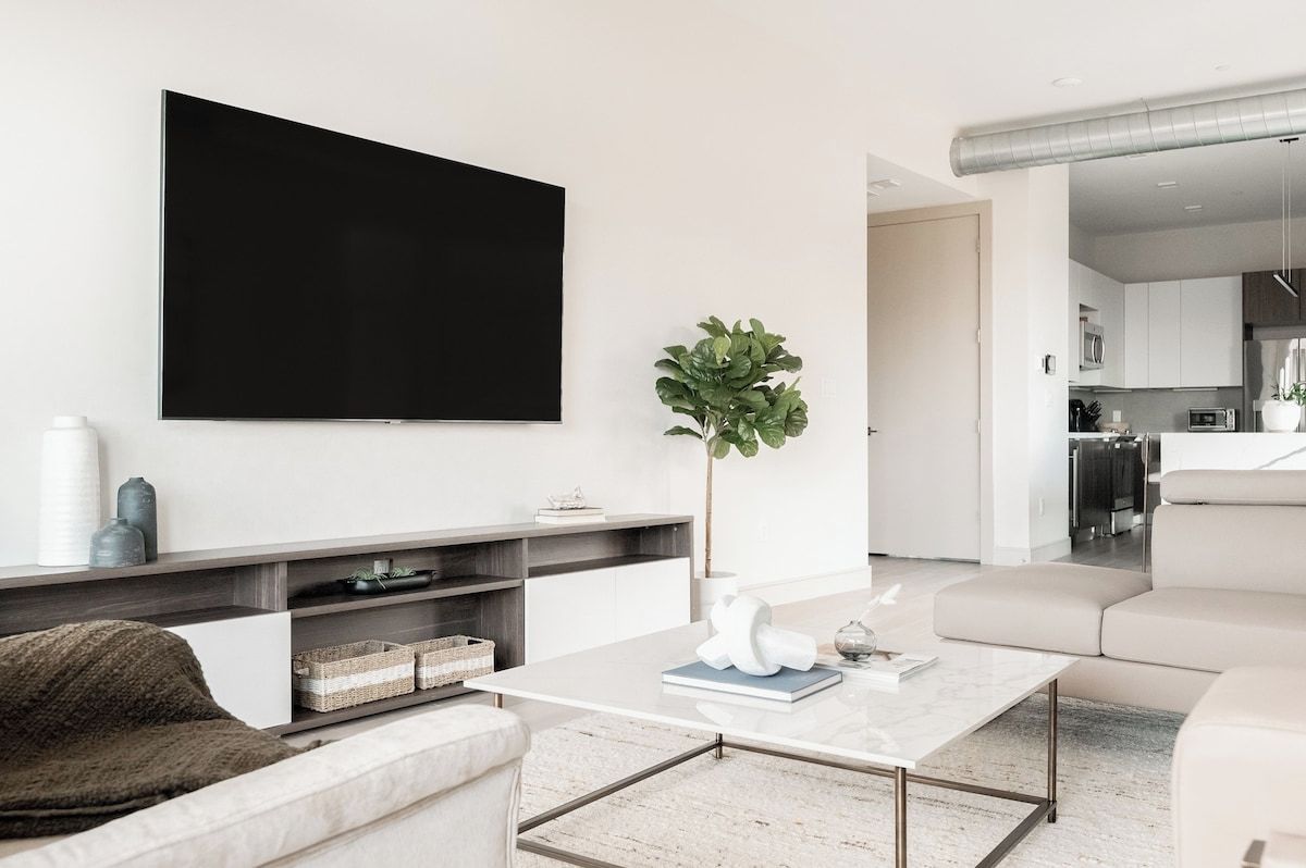 Uma sala de estar moderna com televisão de tela plana, mesa de centro, sofá e planta em vaso.