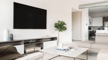 Uma sala de estar moderna com televisão de tela plana, mesa de centro, sofá e planta em vaso.