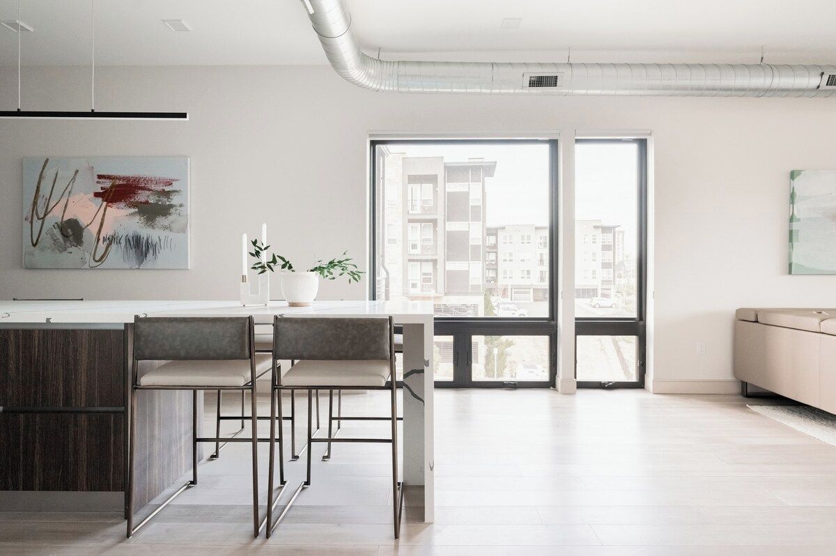 Una cocina moderna con comedor, ventanas amplias y vistas a edificios.