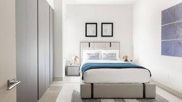 A modern bedroom with a bed, bedside tables, and a large window.