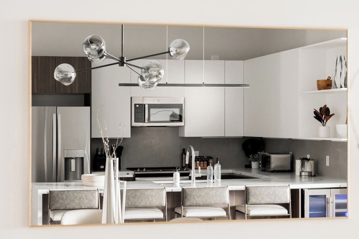 A modern kitchen with a central island, stainless steel appliances, and a pendant light with multiple bulbs.