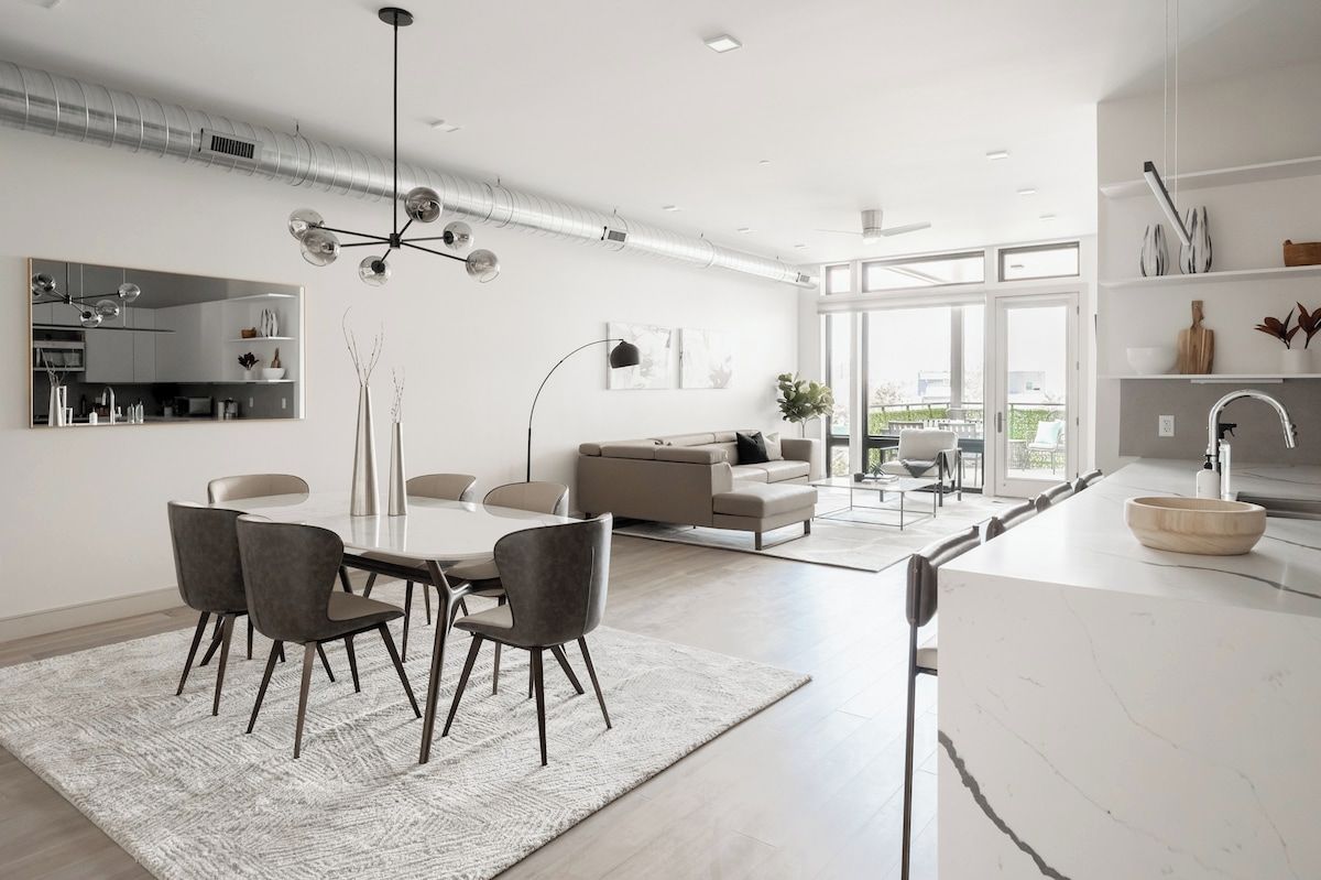 A modern kitchen with a white countertop, a sink, and a dining area with a table and chairs.