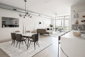 A modern kitchen with a white countertop, a sink, and a dining area with a table and chairs.
