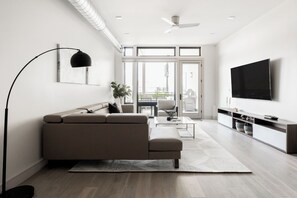 A modern living room with a sofa, coffee table, TV, and a large window.