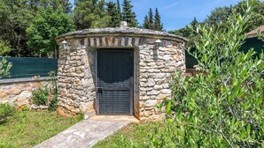 A stone structure with a door, surrounded by greenery and trees. - Villa Oaza - private pool, fitness, near a park forest (Pula)