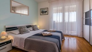 A bedroom with two beds, a large mirror, a framed picture, and a view of the outdoors through sheer curtains. - Villa Oaza - private pool, fitness, near a park forest (Pula)