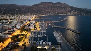 A marina with boats docked, a marina pier, and a cityscape with buildings and mountains in the background. - KEDL Junior Suites 501 (Kalamata)