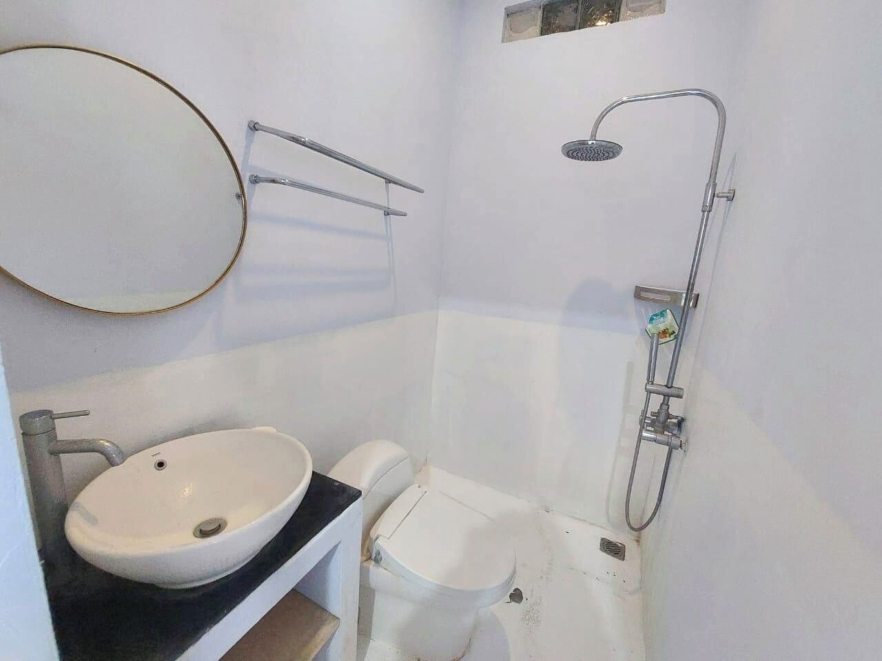 Ein kleines Badezimmer mit weißem Waschbecken, WC und Dusche.