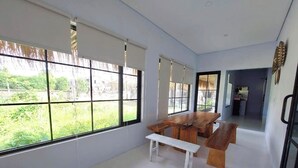 Una habitación amplia con ventanas grandes, una mesa de madera y bancos.
