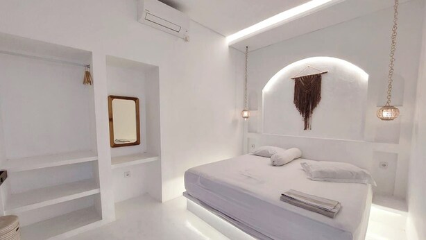 Un dormitorio moderno con una cama grande, estanterías empotradas e iluminación colgante.