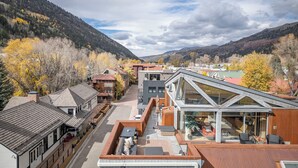 A modern hotel with a rooftop patio, a glass conservatory, and a view of the surrounding mountains and autumn foliage. - Spritz House- 4 Level Telluride Luxury with Penthouse (Telluride)