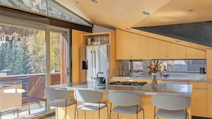 A modern kitchen with a large island, bar stools, and a view of the outdoors. - Spritz House- 4 Level Telluride Luxury with Penthouse (Telluride)