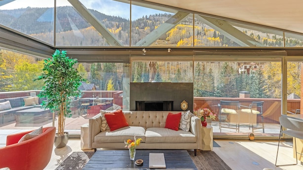 A modern living room with a sofa, red chairs, and a coffee table. A fireplace is visible in the background. - Spritz House- 4 Level Telluride Luxury with Penthouse (Telluride)