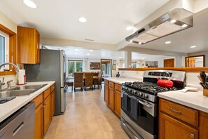 A modern kitchen with stainless steel appliances, wooden cabinets, and a dining area with wicker chairs.